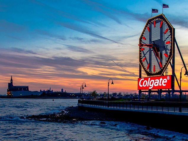 tengerpart, Colgate logó a háttérben egy nagy, piros mutatós óra alatt